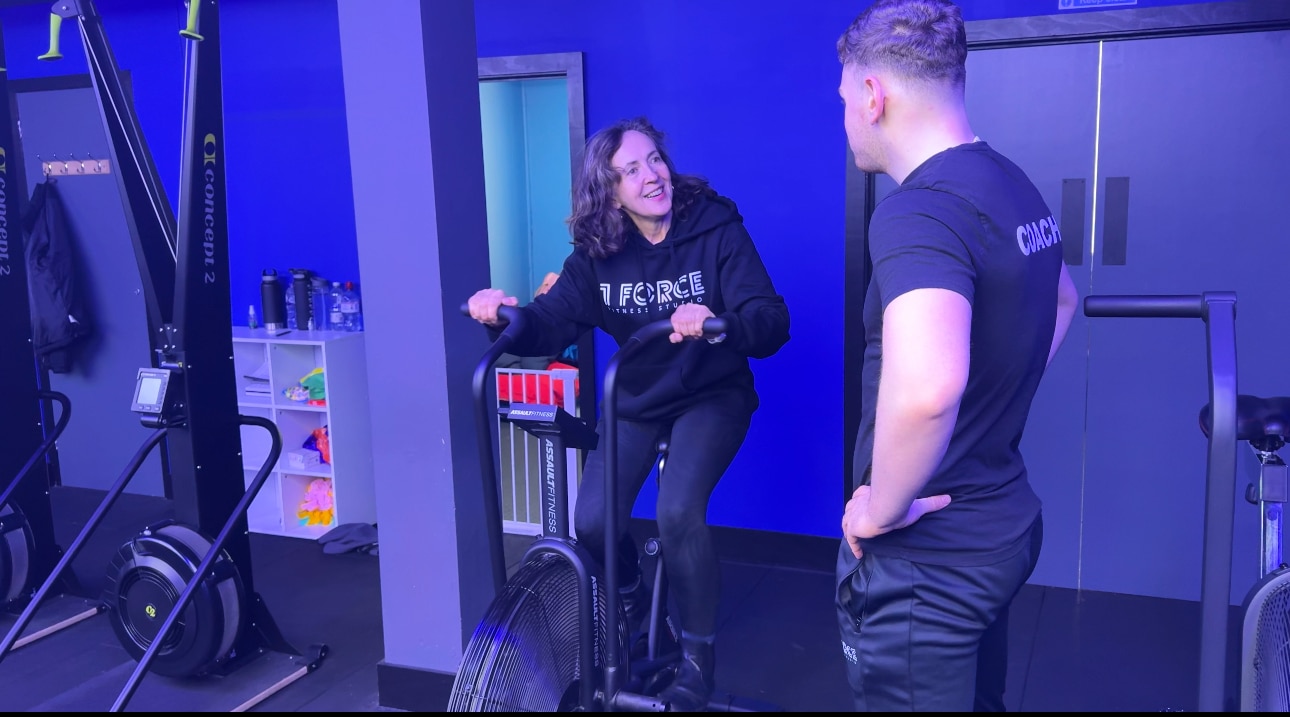 Personal trainer working with client on air bike